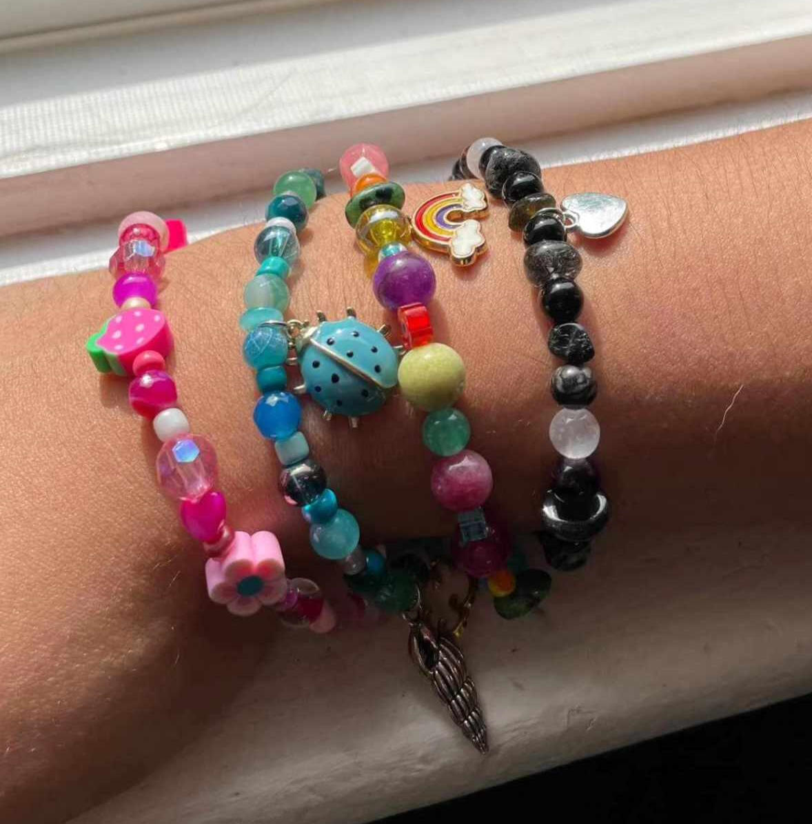a picture of someone's wrist, wearing 4 colorful bracelets
